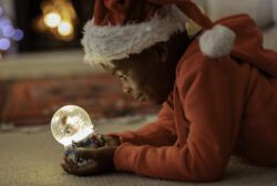 Child in santa hat looking at snow globe