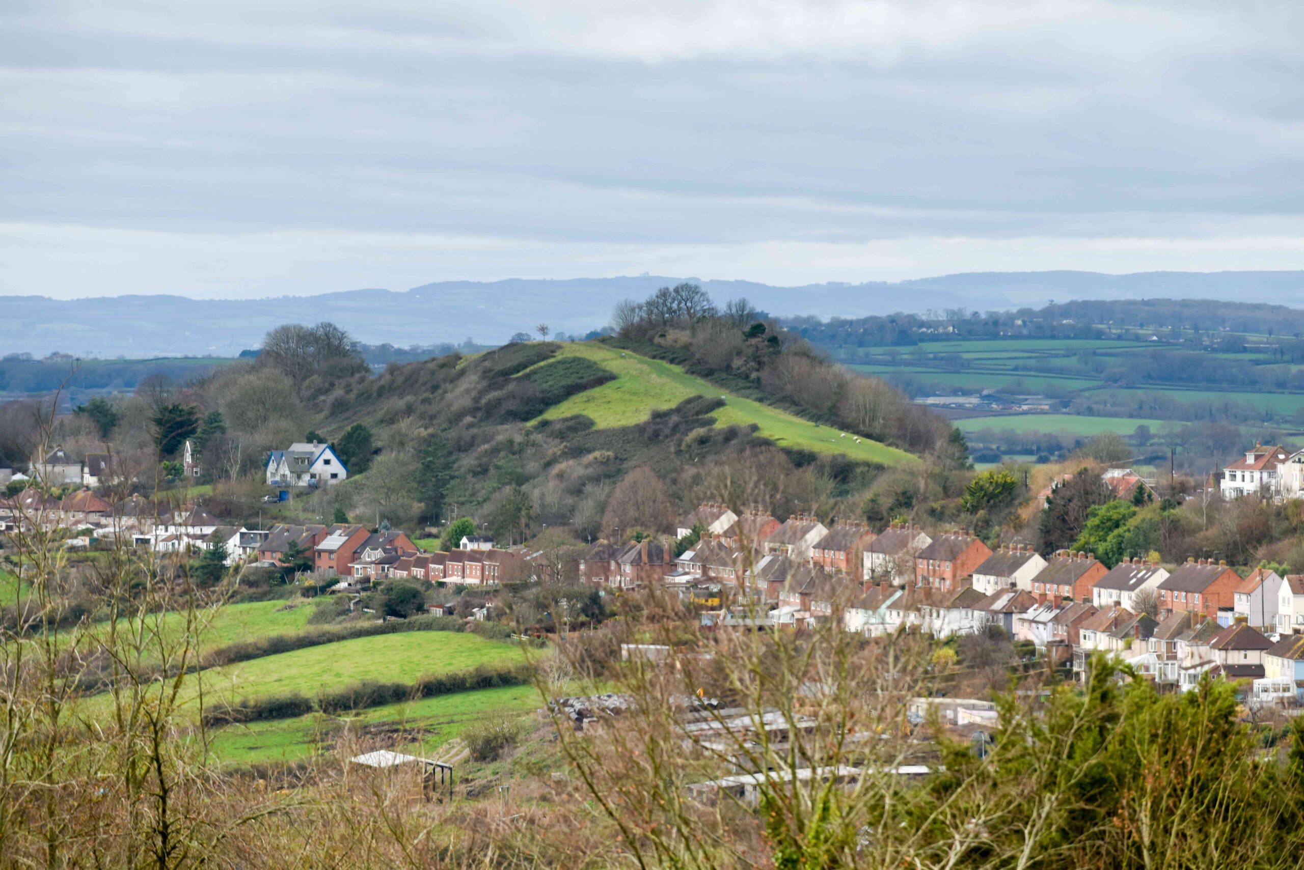 High angle view of scenery with small english town or village in the countryside with hills and fields