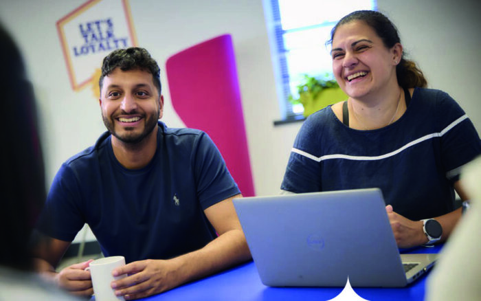 Two people sitting at a desk smiling