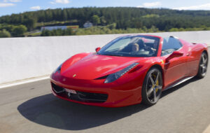 Spa, Belgium - September 27, 2015: Red Ferrari 458 Spider convertible sports car. The 458 Spider is the convertible version of the Ferrari 458 Italia V8 sports car. The car is driving around the race track during the 2015 Spa Italia event at the Spa Francorchamps race track.